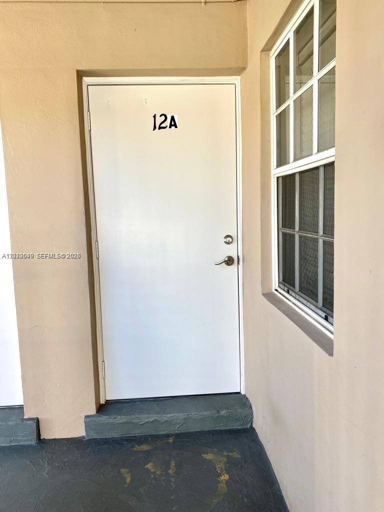 A white exterior door labeled 12A is positioned next to a window on a porch — 6565 Santona St, Coral Gables FL 33146, CORAL GABLES, FL