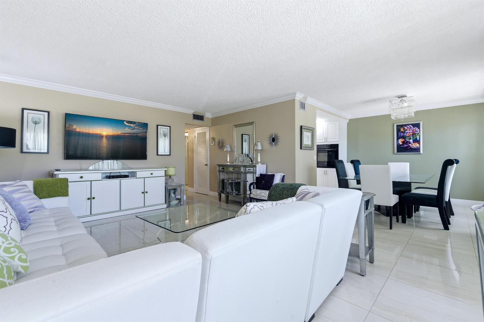 A living room and dining area with white tile floors, white furniture, and neutral walls — 213 Wellington E, West Palm Beach FL 33417, WEST PALM BEACH, FL