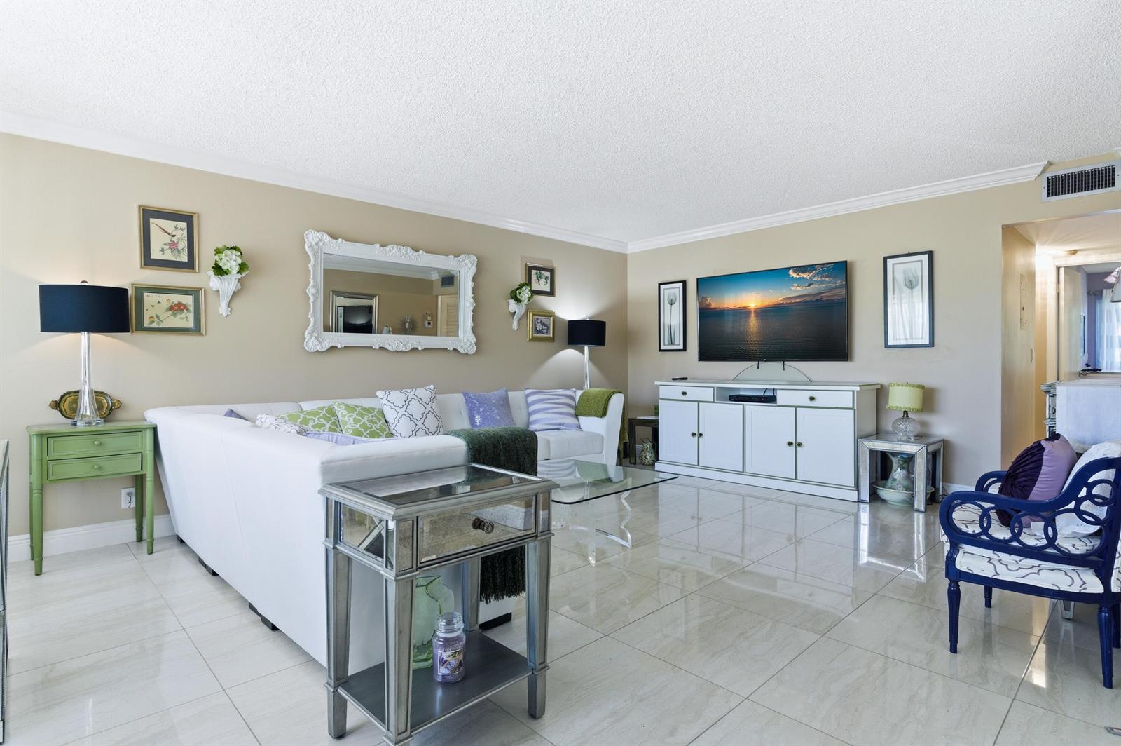A living room features a white sectional sofa, mirrored side tables, and a wall-mounted television — 213 Wellington E, West Palm Beach FL 33417, WEST PALM BEACH, FL