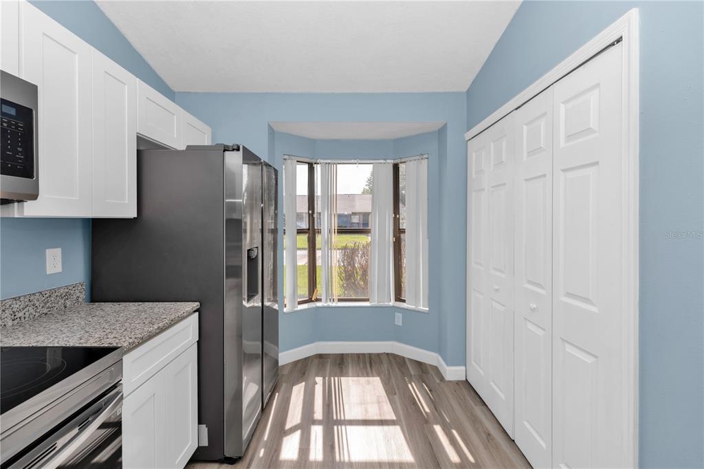 A kitchen with white cabinets, stainless steel appliances, granite countertops, and a bay window — 2501 KING OAK CIRCLE, ST CLOUD, FL