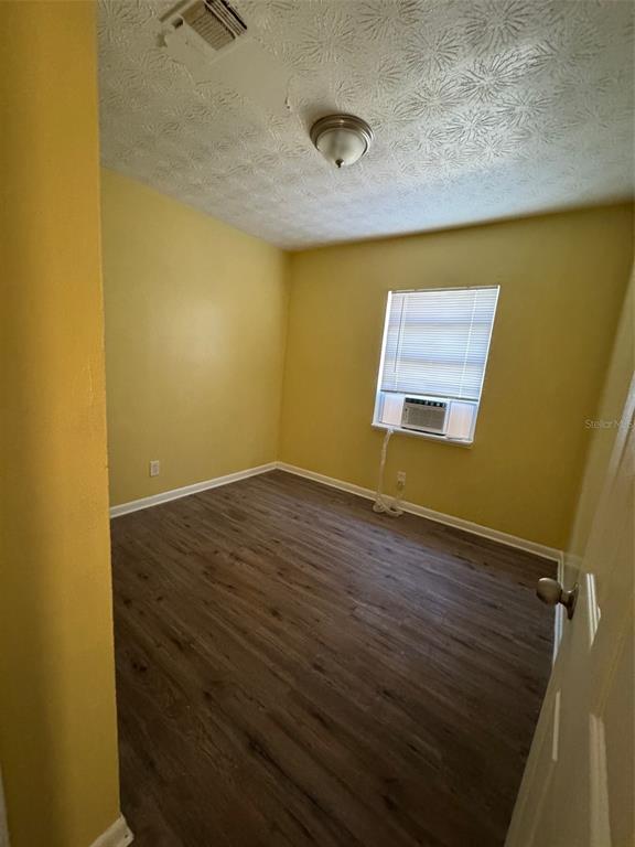 A bedroom with yellow walls, wood-look flooring, a ceiling light, and a window air conditioner — 1109 PHELPS STREET, JACKSONVILLE, FL