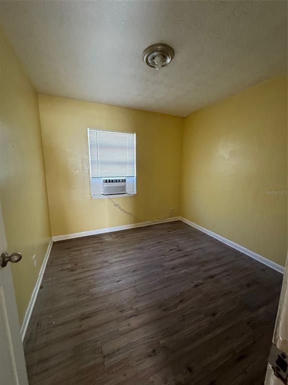 An empty bedroom with yellow walls, wood-look flooring, and a window air conditioning unit — 1109 PHELPS STREET, JACKSONVILLE, FL