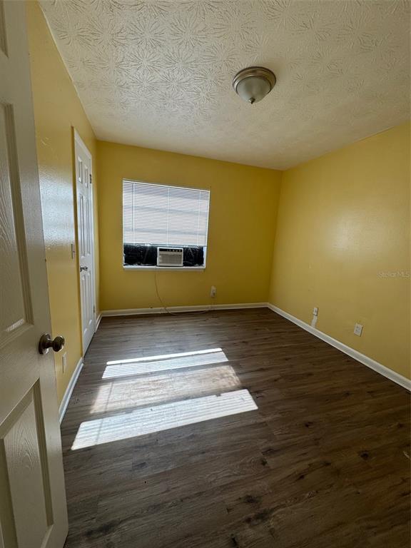 An empty bedroom with yellow walls, wood-look flooring, a window air conditioner, and a ceiling light — 1109 PHELPS STREET, JACKSONVILLE, FL