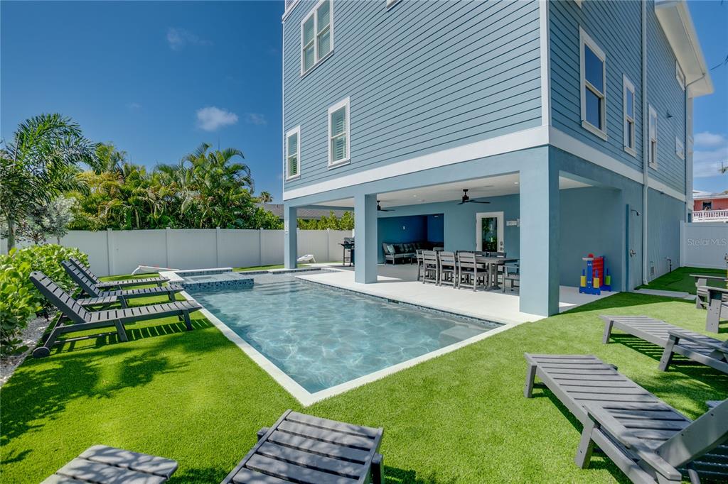 A blue house with a covered patio, swimming pool, and lounge chairs on artificial turf — 2102 AVENUE B, BRADENTON BEACH, FL