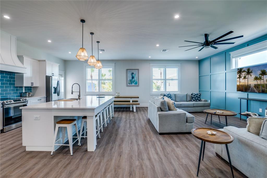 An open-concept kitchen and living area features a large island, blue accent wall, and wood-look flooring — 2102 AVENUE B, BRADENTON BEACH, FL