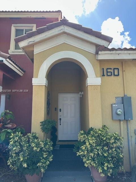 The exterior entrance of a house features a yellow stucco facade and a white door — 160 SW 16th Ave, Homestead FL 33030, HOMESTEAD, FL