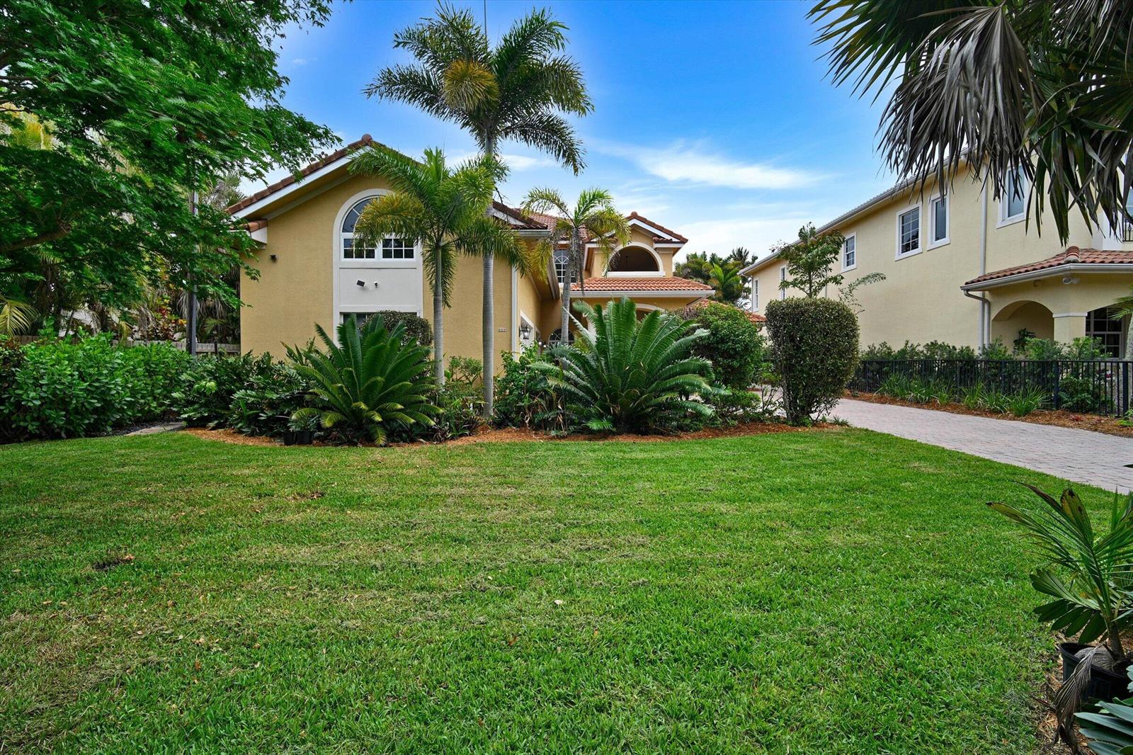 A two-story yellow house with a tile roof, palm trees, and a green lawn — 881 SE Saint Lucie Boulevard, Stuart FL 34996, STUART, FL