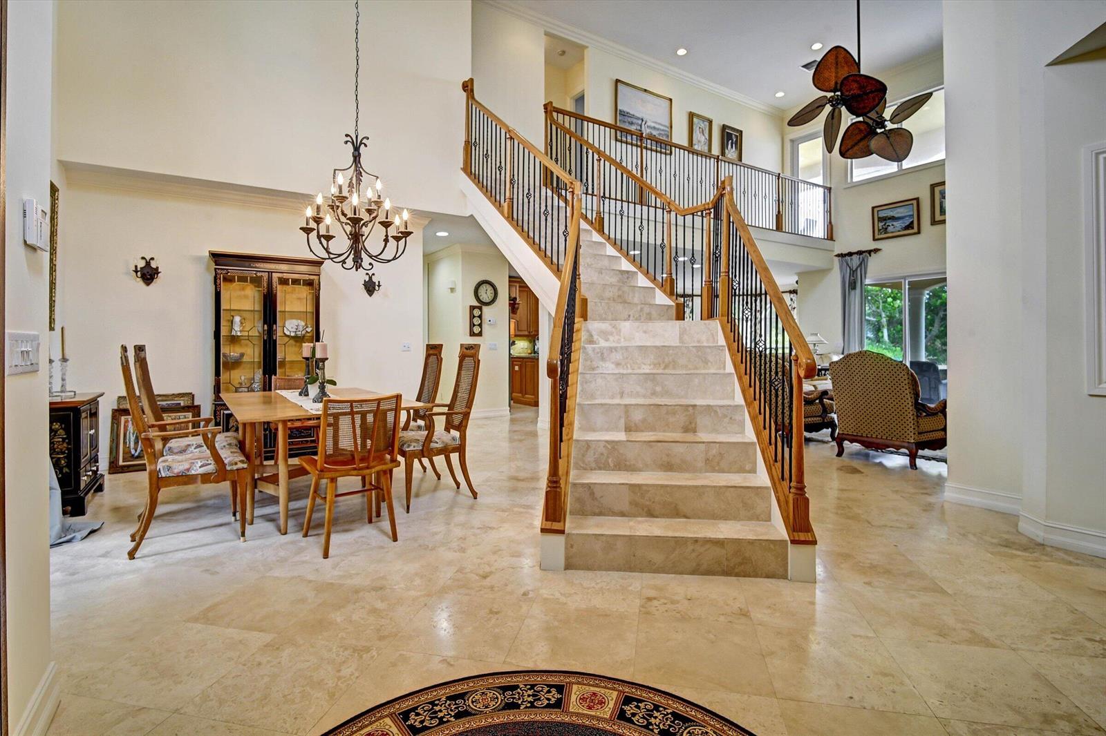 A grand foyer features a stone staircase, tile flooring, a dining area, and a chandelier — 881 SE Saint Lucie Boulevard, Stuart FL 34996, STUART, FL