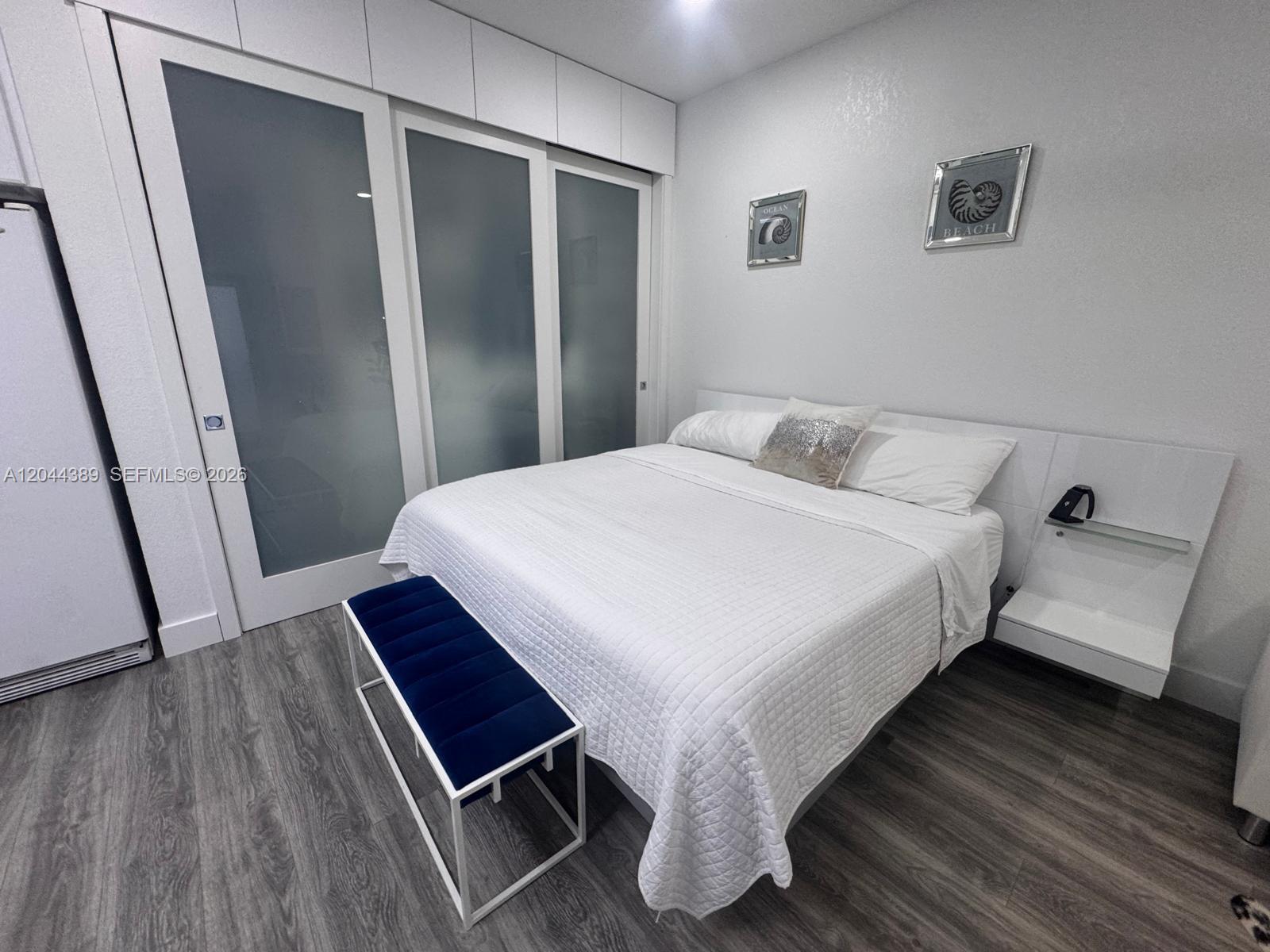 A bedroom features a white bed, a blue bench, and sliding glass closet doors — 3265 SW 153rd Pl # 1, Miami FL 33185, MIAMI, FL