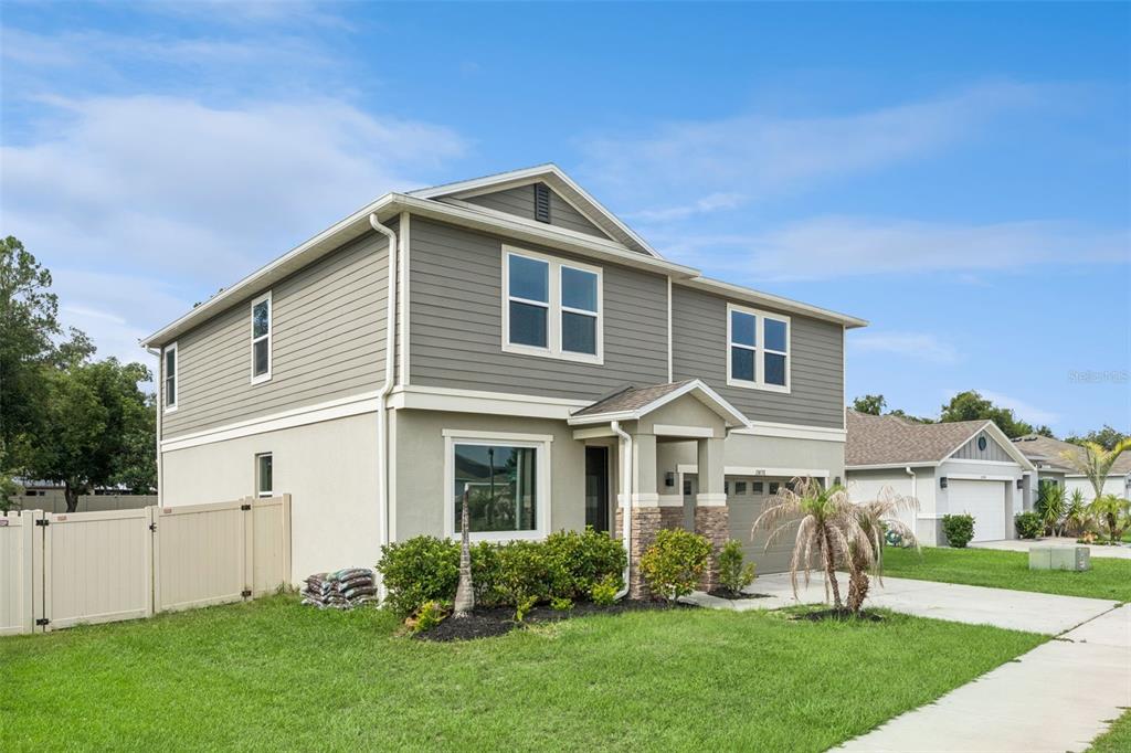 A two-story house with grey horizontal siding, a tan stucco base, and a stone-accented entryway — 15898 BRADICKS COURT, CLERMONT, FL