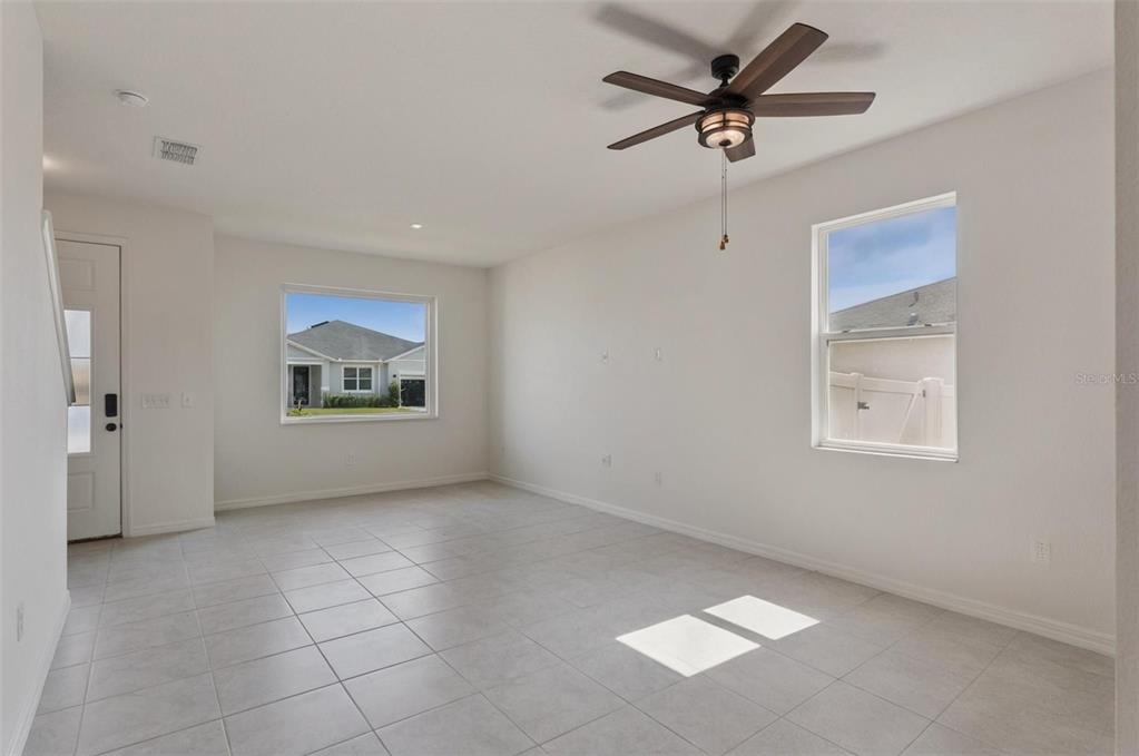 An empty room with white walls, tile flooring, a ceiling fan, and two windows — 15898 BRADICKS COURT, CLERMONT, FL
