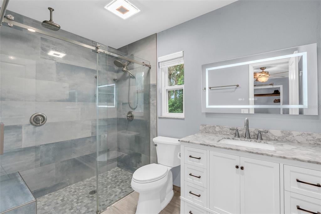 A bathroom features a glass-enclosed walk-in shower, a white vanity with marble top, and toilet — 130 SLADE DRIVE, LONGWOOD, FL