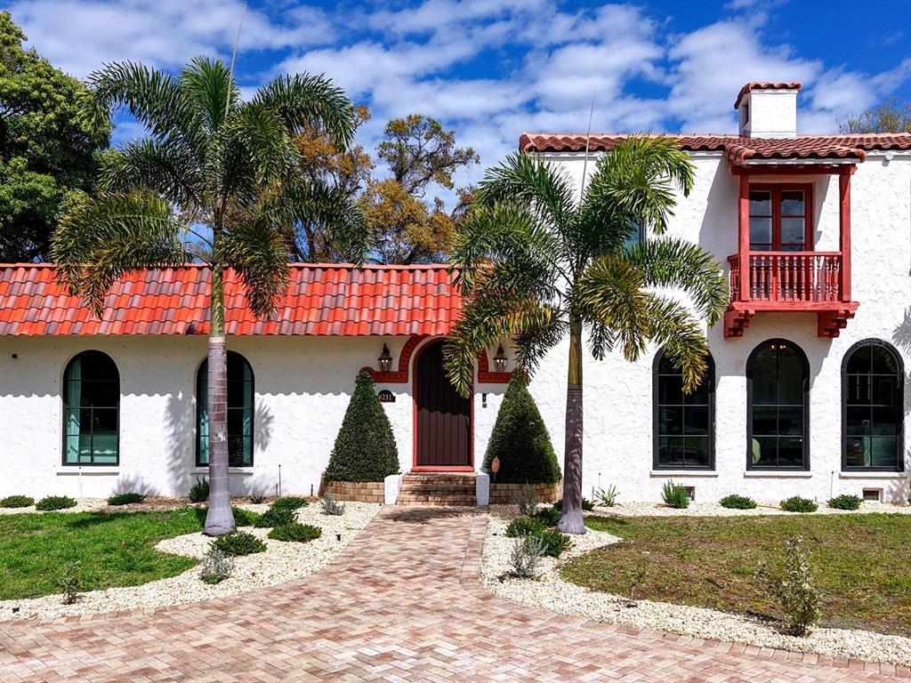 A white Spanish-style house with a red tile roof, arched windows, and two palm trees — 6251 10TH AVENUE S, GULFPORT, FL
