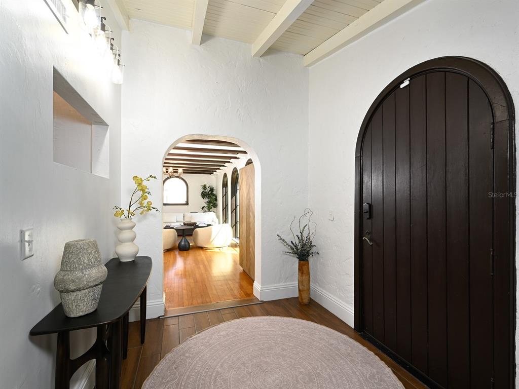 An entryway features a dark arched door, white textured walls, and a wood-floored transition — 6251 10TH AVENUE S, GULFPORT, FL