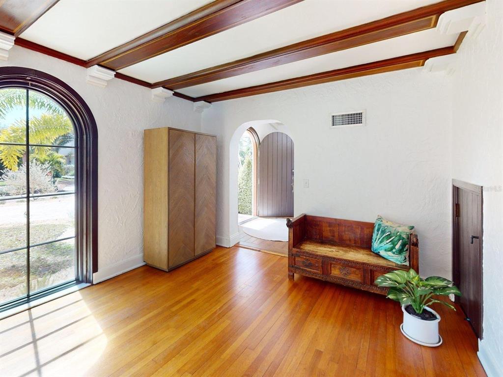 A room with hardwood floors, a beamed ceiling, an arched window, and a wooden bench — 6251 10TH AVENUE S, GULFPORT, FL