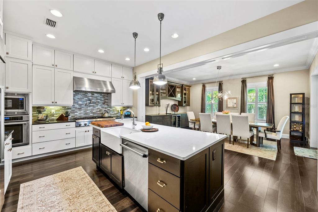 A kitchen with white upper cabinets, a dark island, and an adjacent dining area — 3211 W BAY VILLA AVENUE, TAMPA, FL