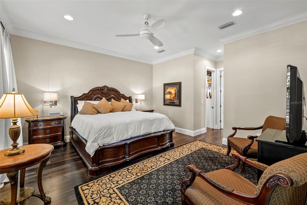 A bedroom features a wooden bed frame, dark hardwood floors, and a patterned area rug — 3211 W BAY VILLA AVENUE, TAMPA, FL