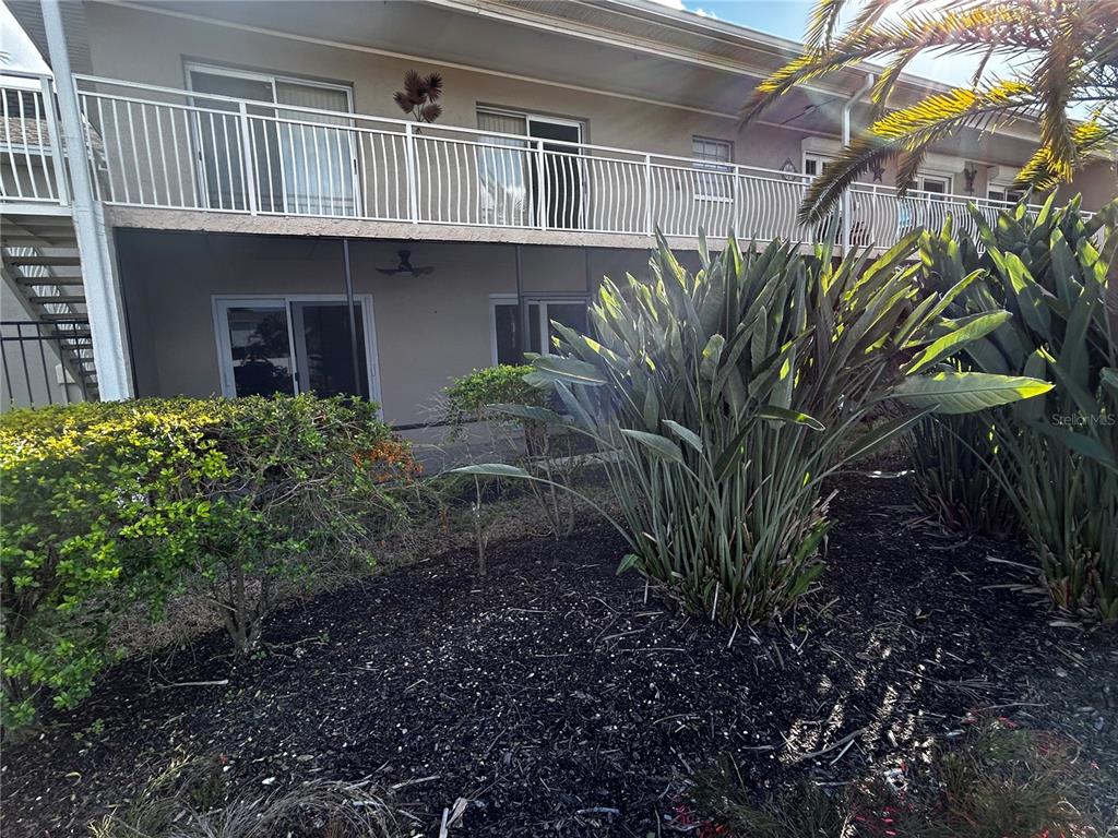A two-story apartment building features a screened-in ground floor patio and an upper balcony — 8802 BAY POINTE DRIVE UNIT 102, TAMPA, FL