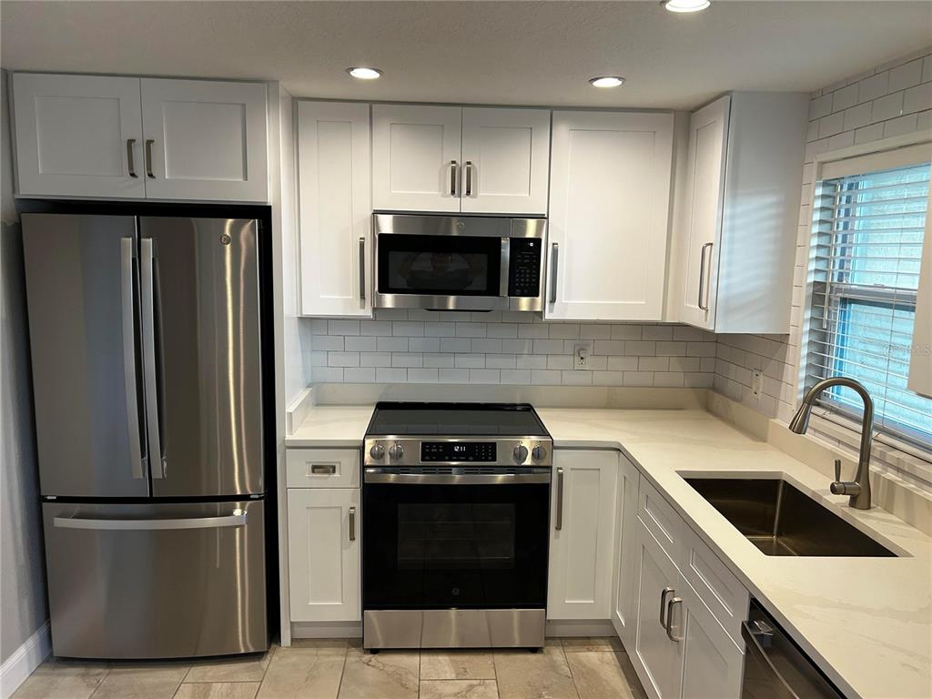 A kitchen with white cabinets, stainless steel appliances, and light-colored countertops — 8802 BAY POINTE DRIVE UNIT 102, TAMPA, FL