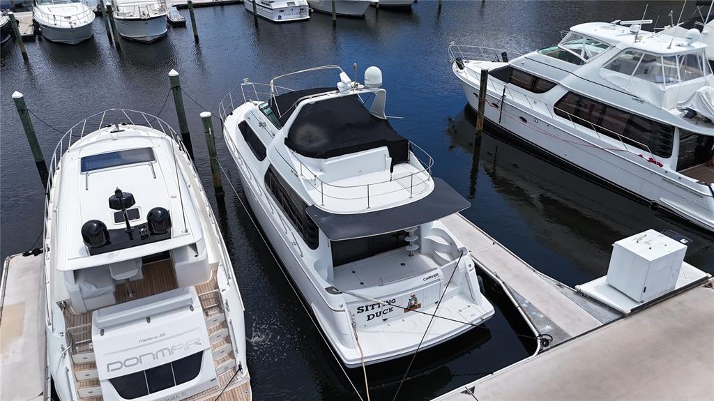 An aerial view shows three white yachts docked side-by-side in a marina — 102 RIVIERA DUNES WAY UNIT C-50, PALMETTO, FL