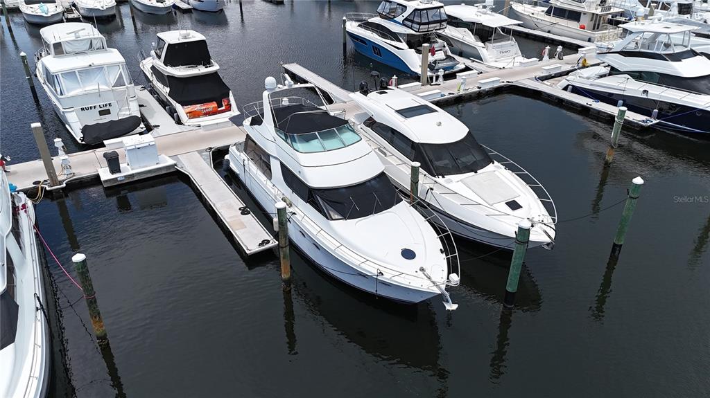 An aerial view shows several white motor yachts docked at a marina — 102 RIVIERA DUNES WAY UNIT C-50, PALMETTO, FL
