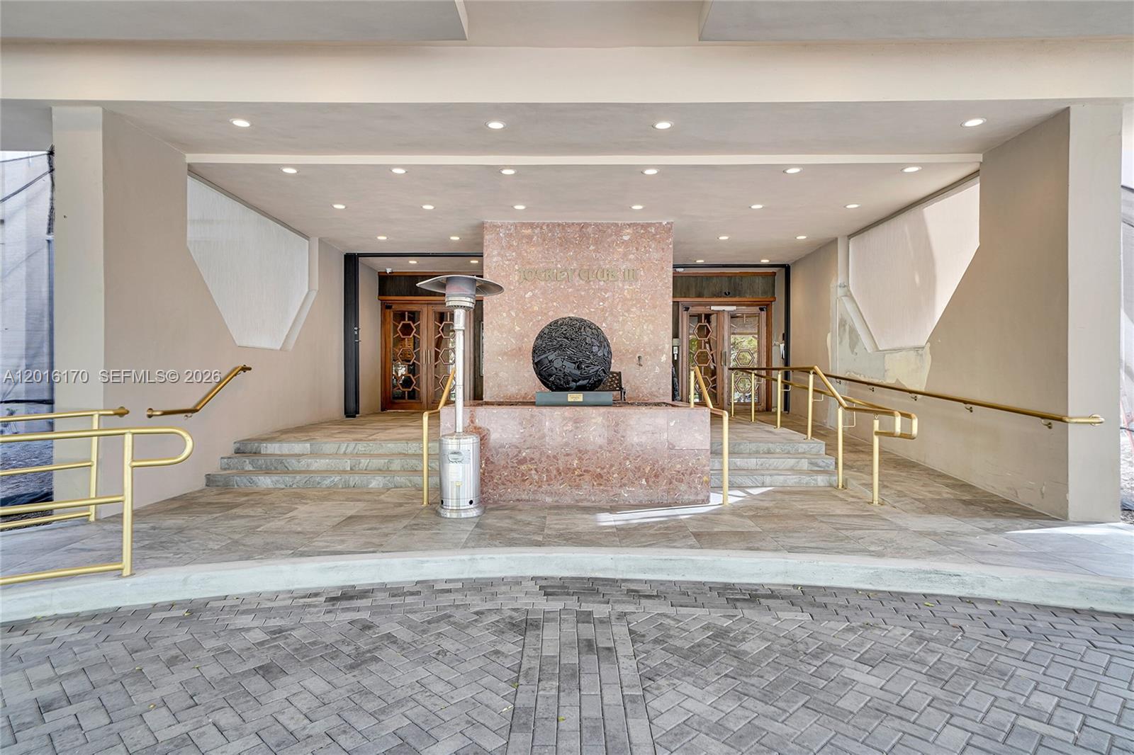 The exterior entrance features a stone-tiled driveway, a central sculpture, and gold-colored handrails — 11113 Biscayne Blvd # 255, Miami FL 33181, MIAMI, FL