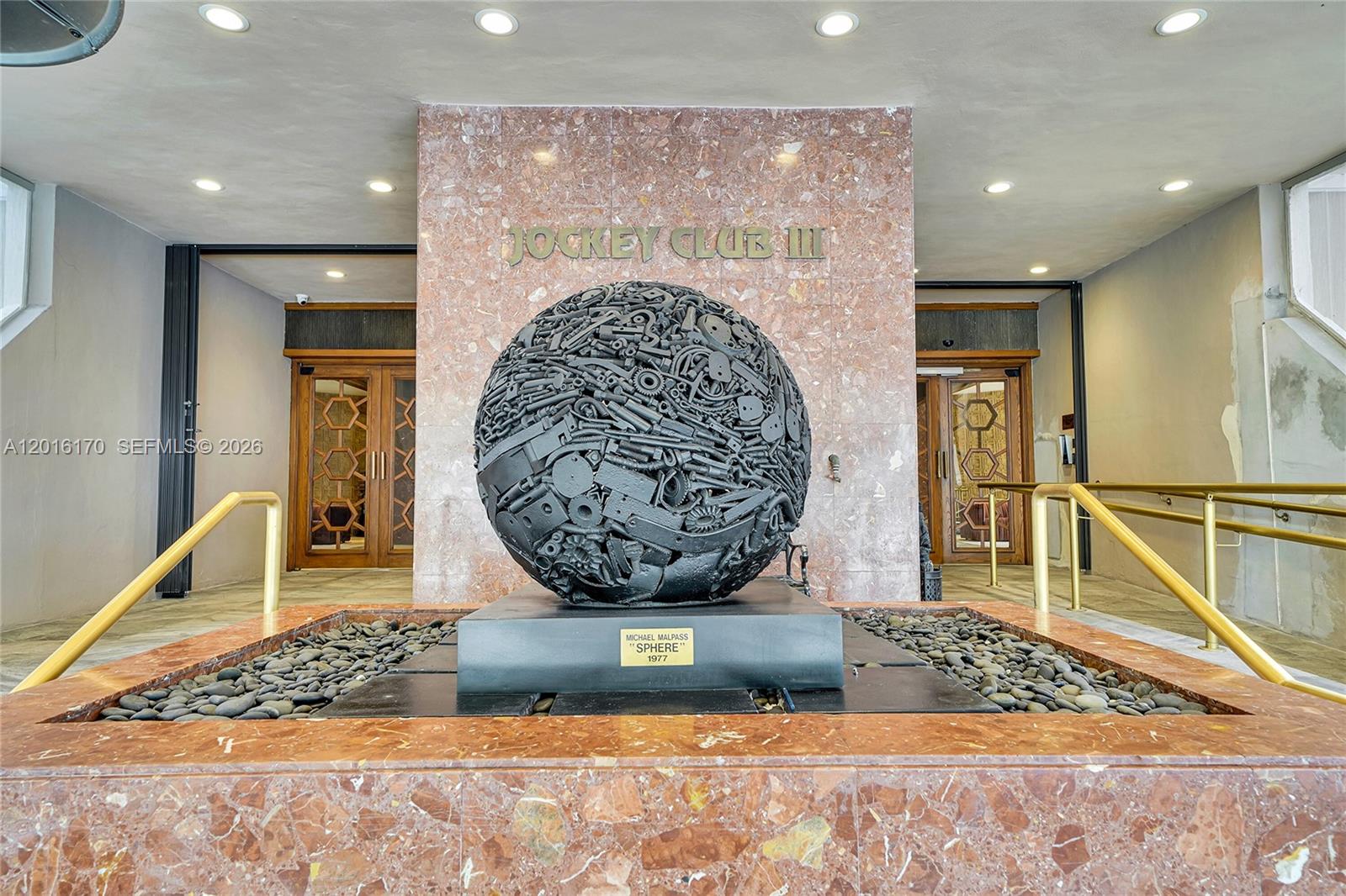 A large metal sphere sculpture sits in a stone fountain before a building entrance — 11113 Biscayne Blvd # 255, Miami FL 33181, MIAMI, FL