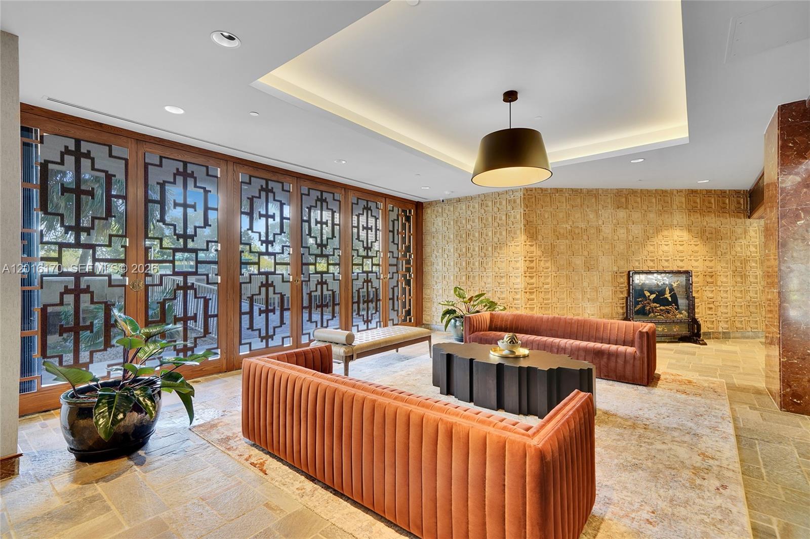 A lounge area features two orange velvet sofas, a dark coffee table, and patterned glass doors — 11113 Biscayne Blvd # 255, Miami FL 33181, MIAMI, FL