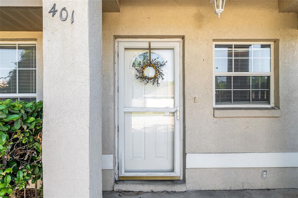 A beige stucco exterior features a front door with a wreath and a nearby window — 11191 SE 55TH AVENUE ROAD UNIT 401, BELLEVIEW, FL
