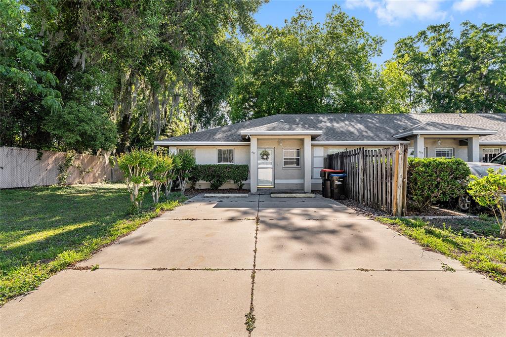 A single-story duplex with a concrete driveway, a small front yard, and mature trees — 11191 SE 55TH AVENUE ROAD UNIT 401, BELLEVIEW, FL