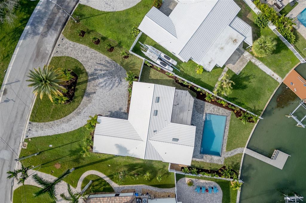 An aerial view shows waterfront homes along a bay with a bridge in the distance — 10350 PARADISE BOULEVARD, TREASURE ISLAND, FL