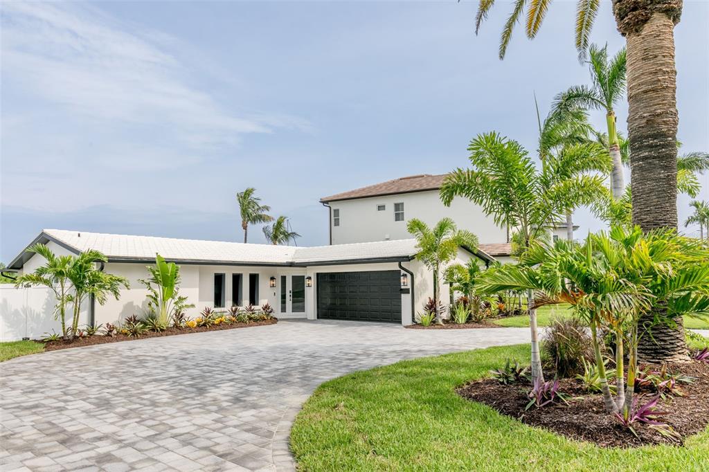 An aerial view shows a house with a white metal roof, pool, and waterfront dock — 10350 PARADISE BOULEVARD, TREASURE ISLAND, FL