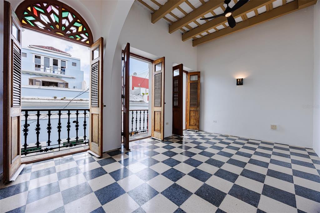 An empty room features a checkered floor, wooden ceiling beams, and doors opening to balconies — 364 CALLE SOL UNIT 2B, OLD SAN JUAN, PR