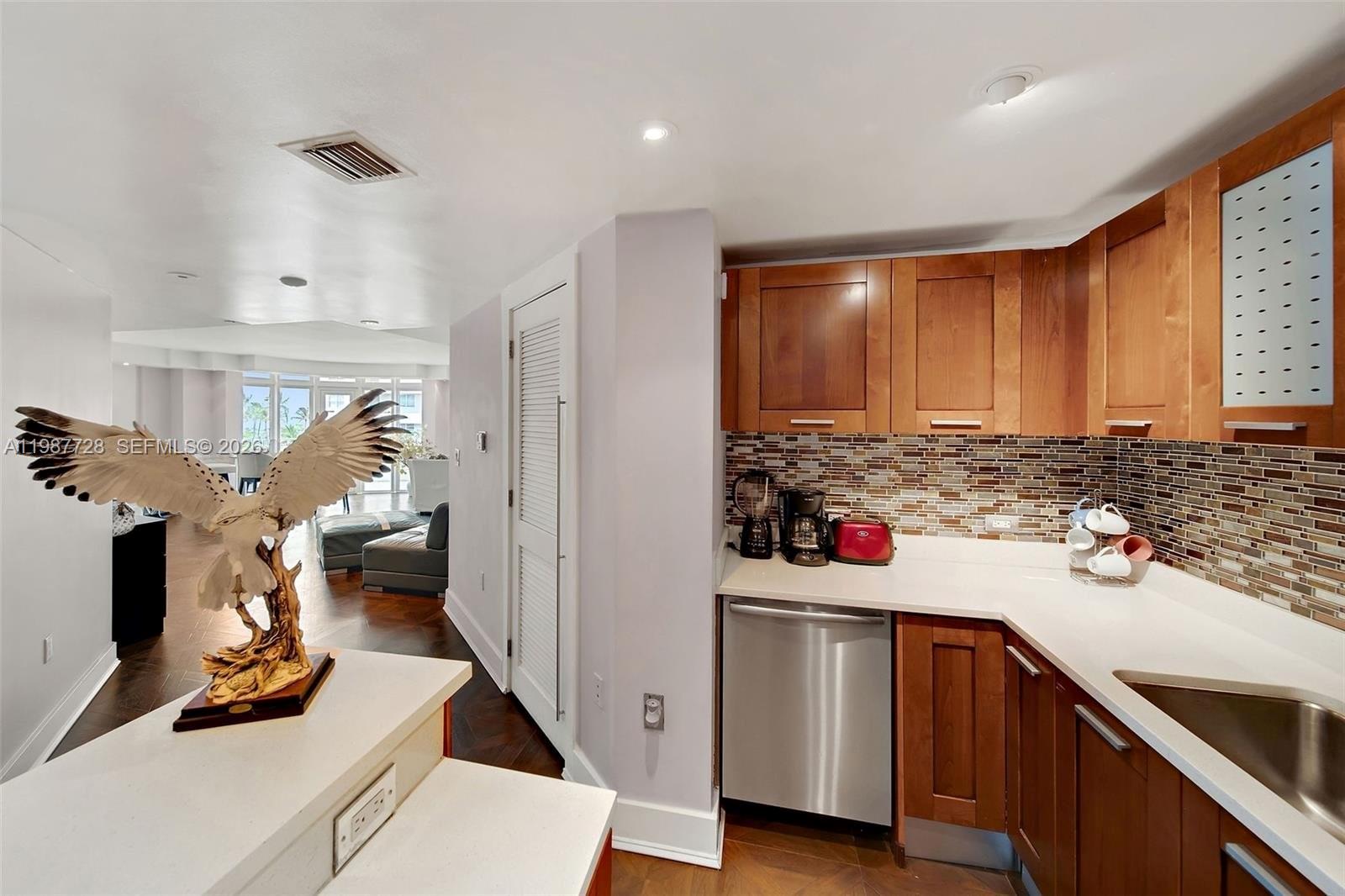 A kitchen with wood cabinets, stainless steel appliances, and a decorative eagle sculpture on the counter — 448 Ocean Dr # 302, Miami Beach FL 33139, MIAMI BEACH, FL