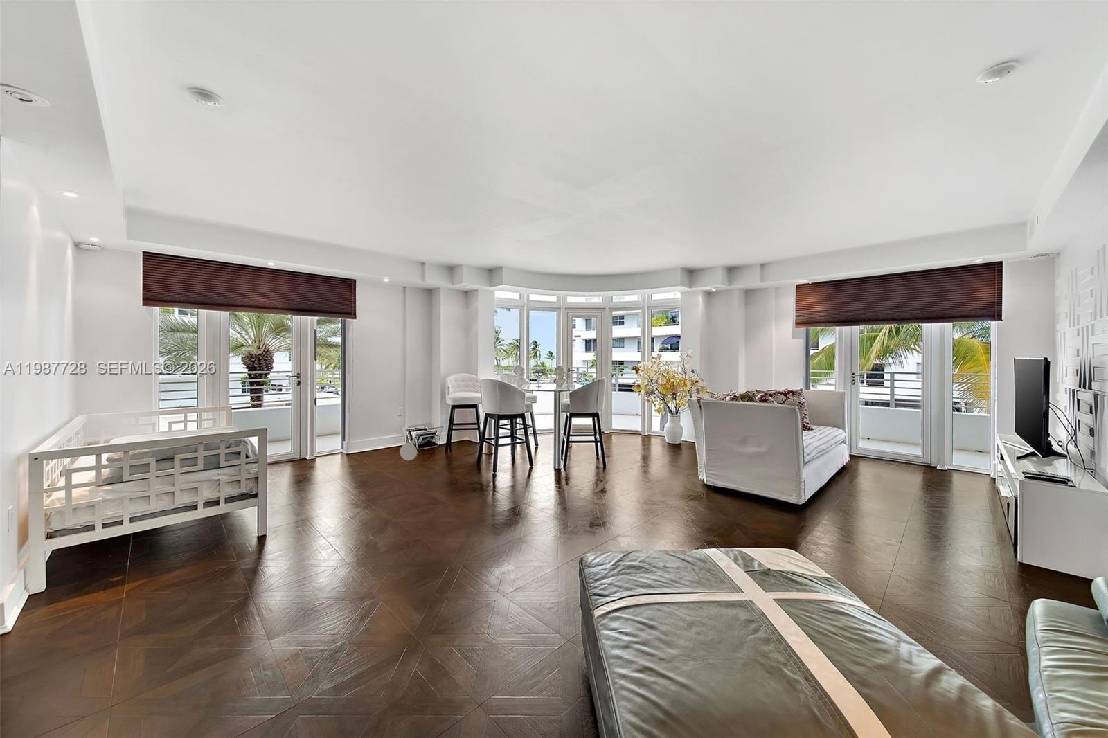 A bright living room features dark hardwood floors, white walls, and floor-to-ceiling glass doors — 448 Ocean Dr # 302, Miami Beach FL 33139, MIAMI BEACH, FL