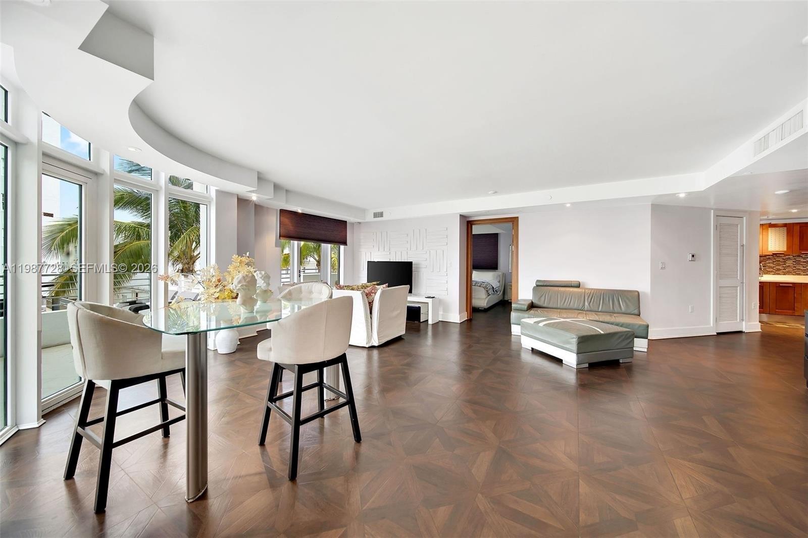 A spacious living and dining area features dark wood flooring, floor-to-ceiling windows, and modern furniture — 448 Ocean Dr # 302, Miami Beach FL 33139, MIAMI BEACH, FL