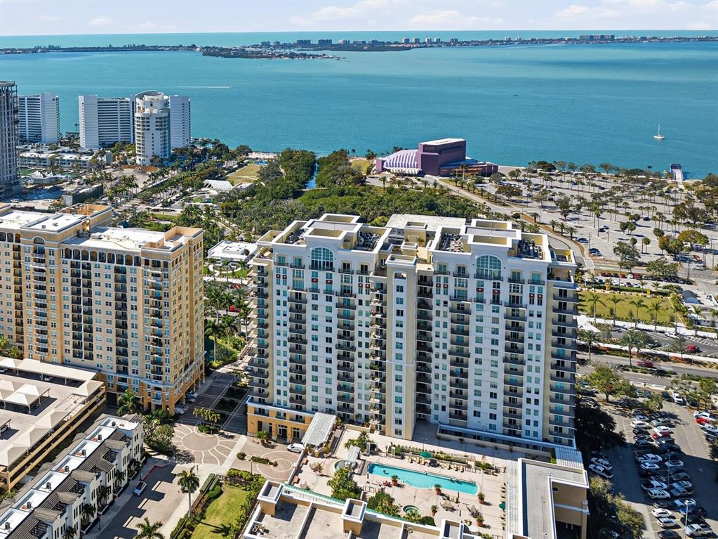 An aerial view shows a high-rise residential building with a pool near a bay — 800 N TAMIAMI TRAIL UNIT 1203, SARASOTA, FL