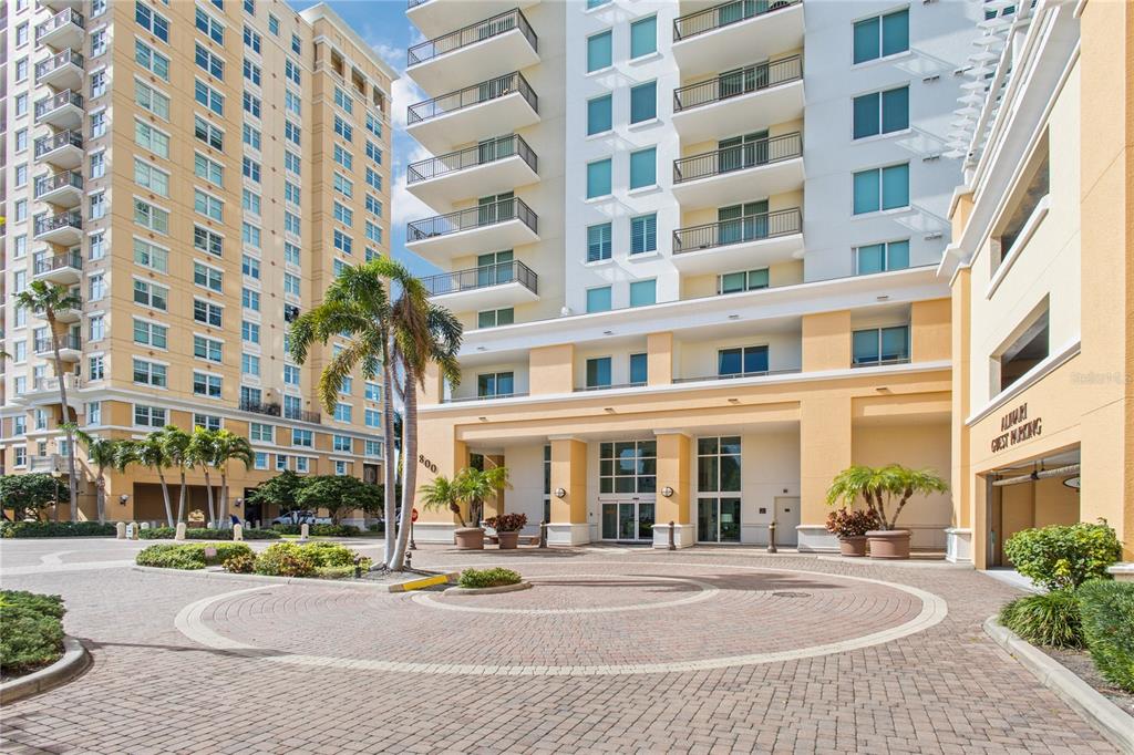 A circular brick driveway leads to the entrance of a multi-story residential building with balconies — 800 N TAMIAMI TRAIL UNIT 1203, SARASOTA, FL