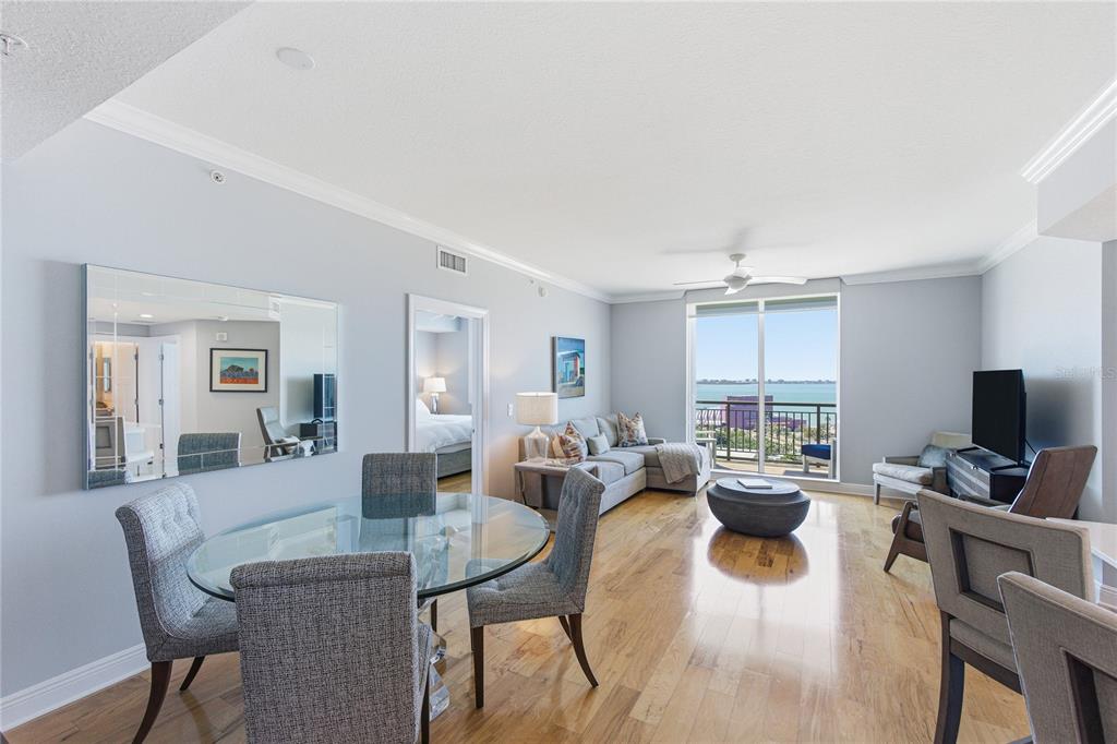 A dining and living area features hardwood floors, a glass table, and a balcony view — 800 N TAMIAMI TRAIL UNIT 1203, SARASOTA, FL