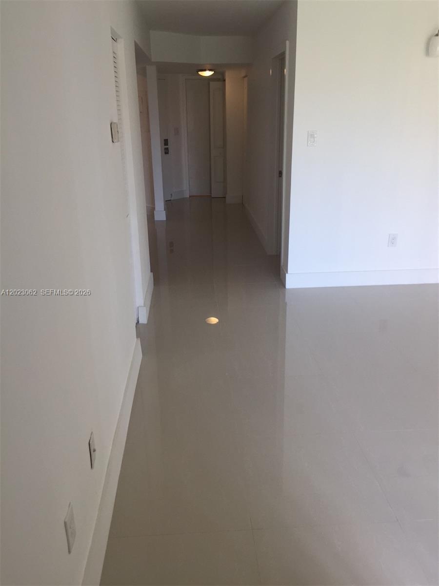 A hallway with light-colored tile flooring leads to a doorway with a light fixture — 4746 NW 97th Ct # 72, Doral FL 33178, DORAL, FL