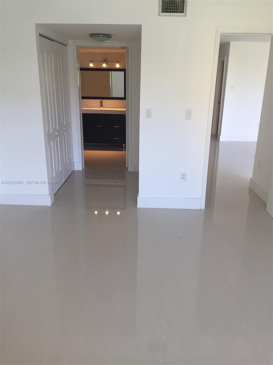 A hallway with white walls and glossy tile flooring leads to a bathroom and bedroom — 4746 NW 97th Ct # 72, Doral FL 33178, DORAL, FL