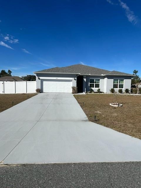 A single-story house with a two-car garage and a concrete driveway under a blue sky — 15610 SW 40TH TERRACE, OCALA, FL