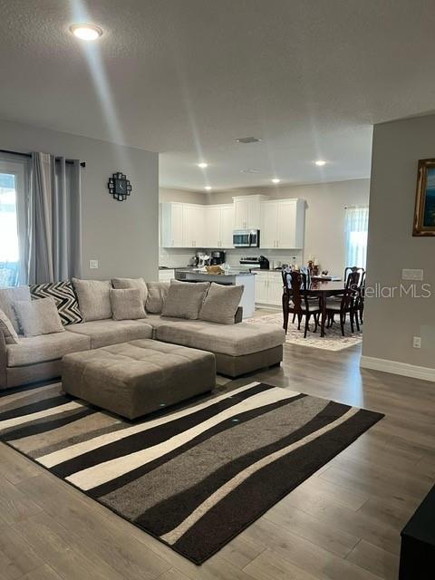 An open-concept living room features a large sectional sofa, a patterned rug, and a kitchen — 15610 SW 40TH TERRACE, OCALA, FL