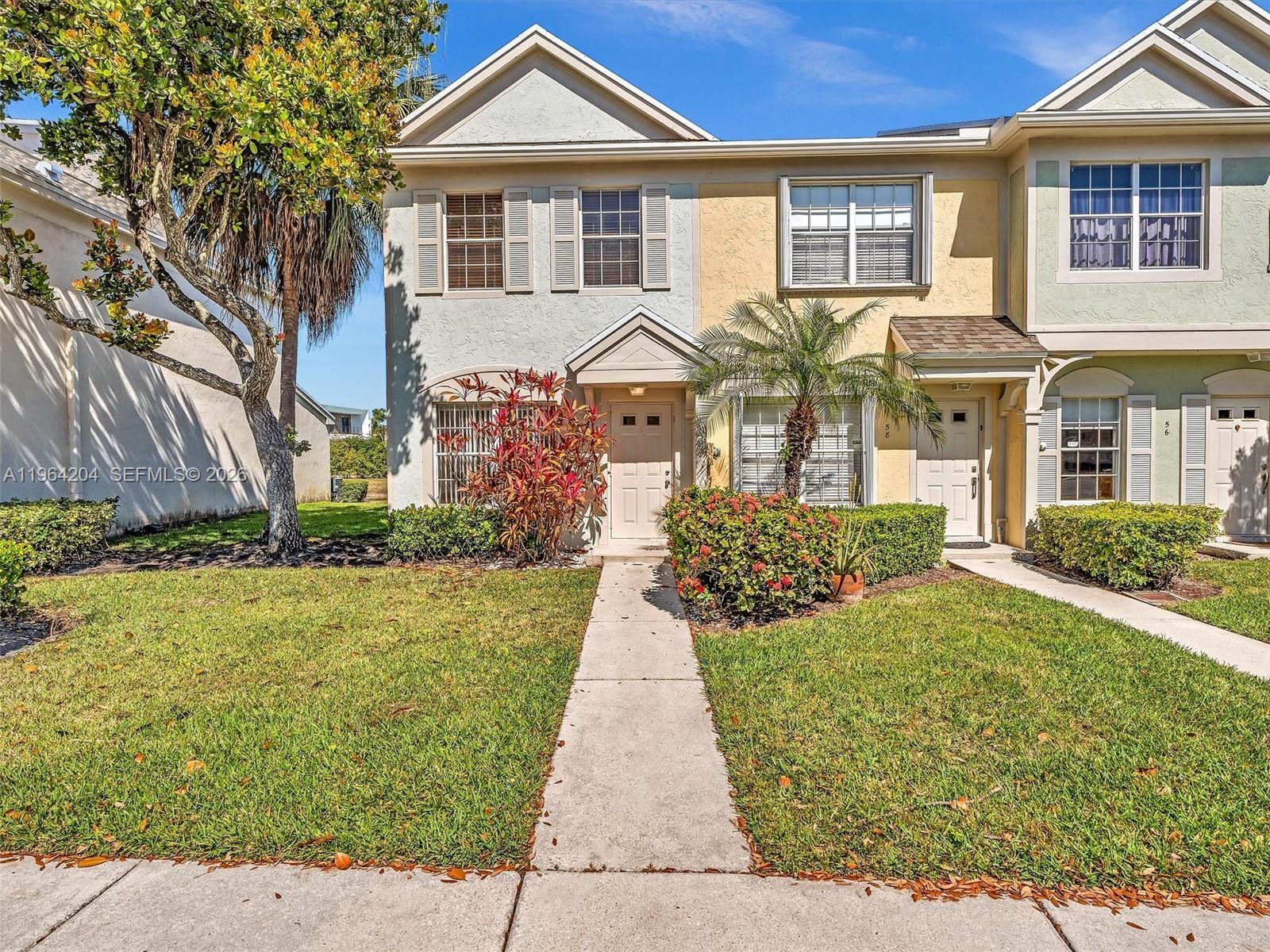 A two-story townhouse with a concrete walkway, landscaped front yard, and light-colored stucco exterior — 60 Key West Ct # 60, Weston FL 33326, WESTON, FL