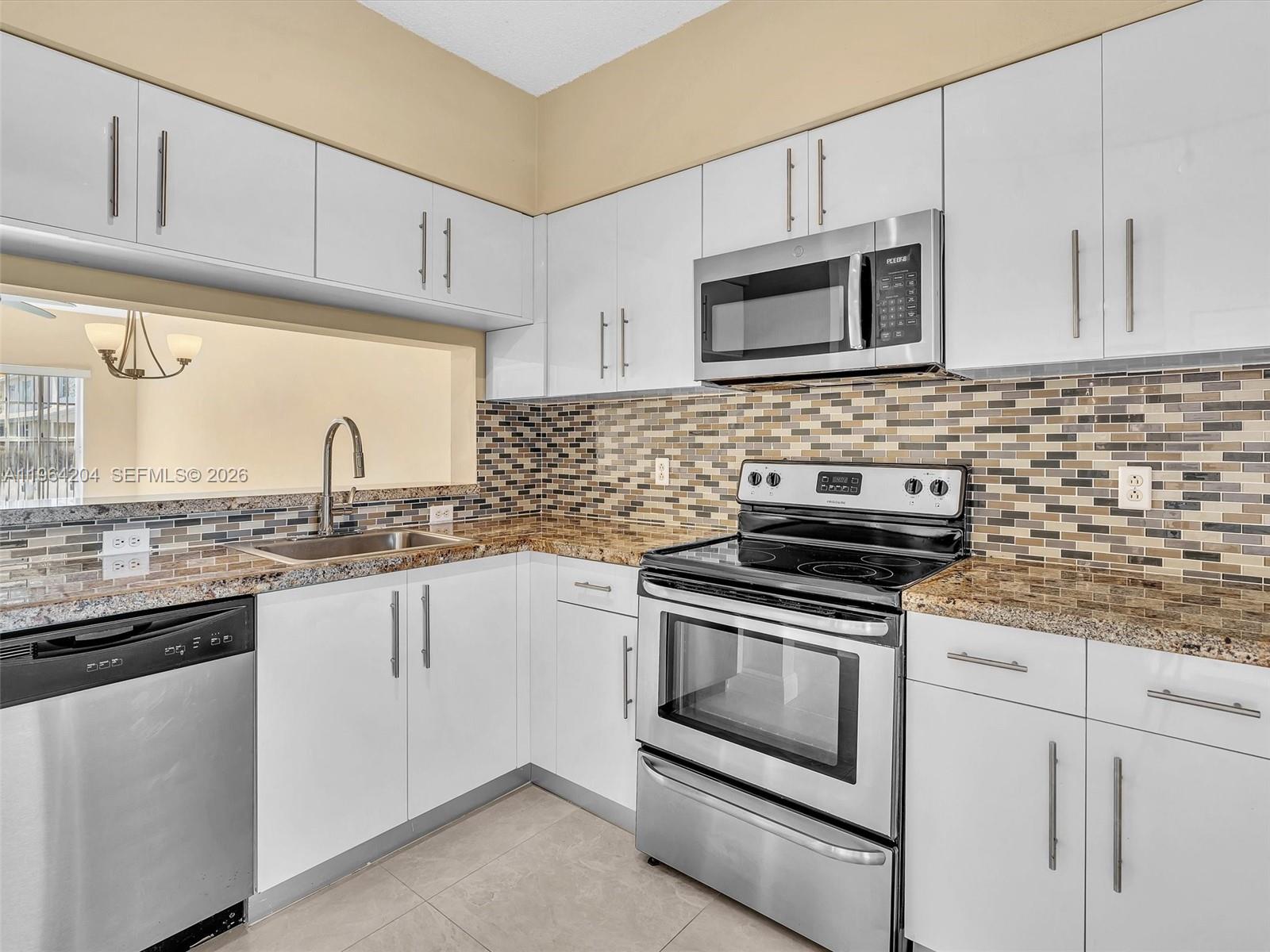 A kitchen features white cabinets, stainless steel appliances, a granite countertop, and a tiled backsplash — 60 Key West Ct # 60, Weston FL 33326, WESTON, FL
