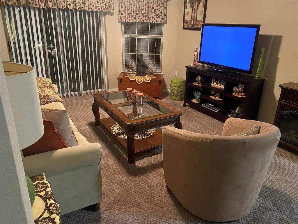 A living room features a sofa, a round armchair, a coffee table, and a television — 5174 NORTHRIDGE ROAD UNIT 211, SARASOTA, FL