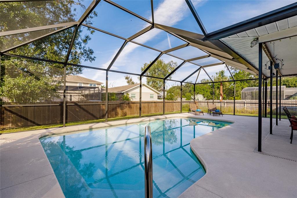 A screened-in swimming pool with a concrete deck and lounge chairs in a backyard — 912 72ND STREET NW, BRADENTON, FL