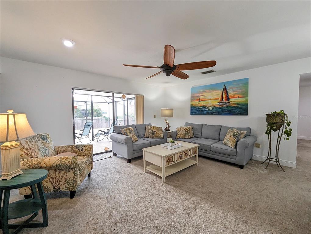 A living room features gray sofas, a patterned armchair, a coffee table, and a ceiling fan — 912 72ND STREET NW, BRADENTON, FL