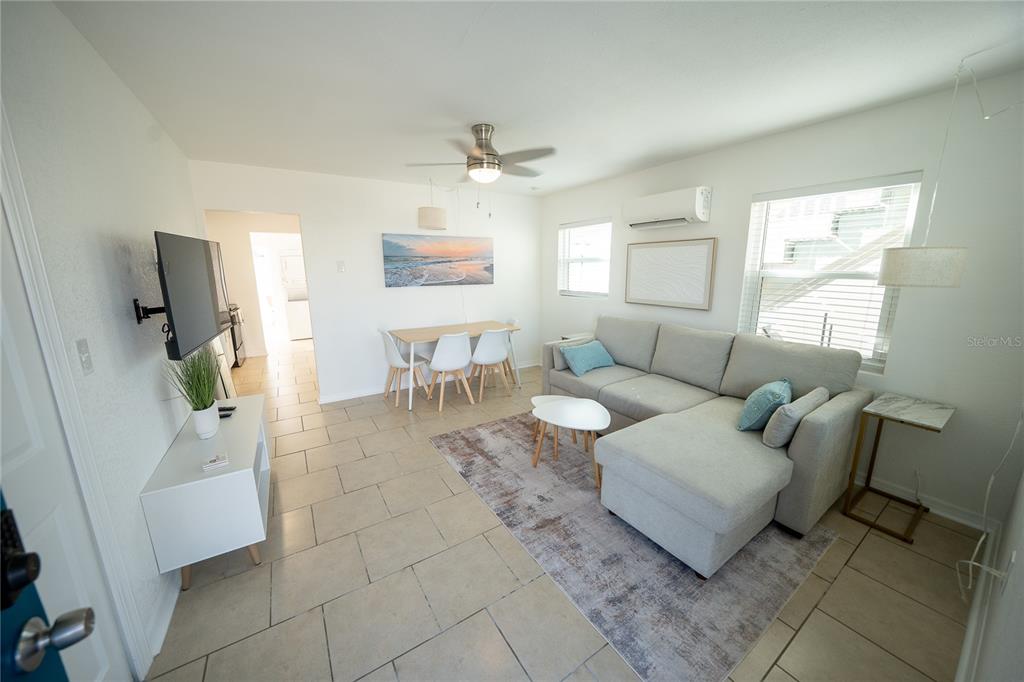 A living room features a sectional sofa, dining area, tile flooring, and a ceiling fan — 130 177TH TER W, REDINGTON SHORES, FL