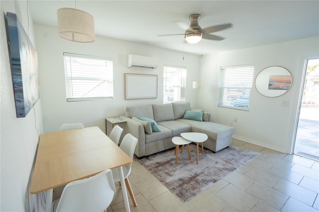 A living and dining area features a light gray sectional sofa, dining table, and tile flooring — 130 177TH TER W, REDINGTON SHORES, FL